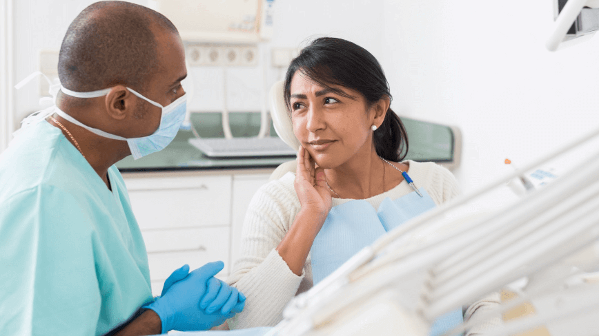 woman holding jaw at dentist